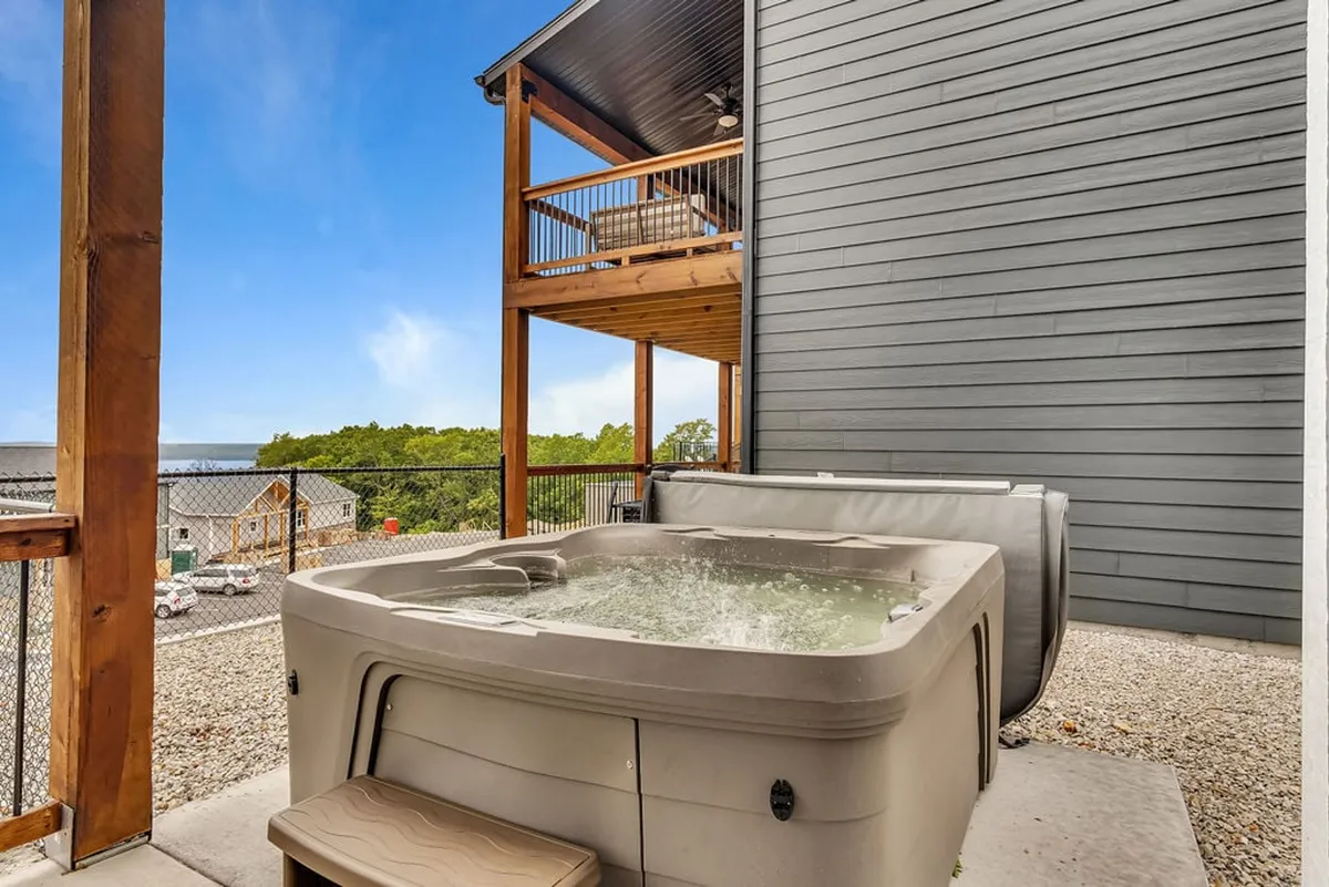The scene focuses on the private hot tub on a deck area, surrounded by trees for a tranquil yet social atmosphere. The setting is designed for relaxation after an active day indoors.