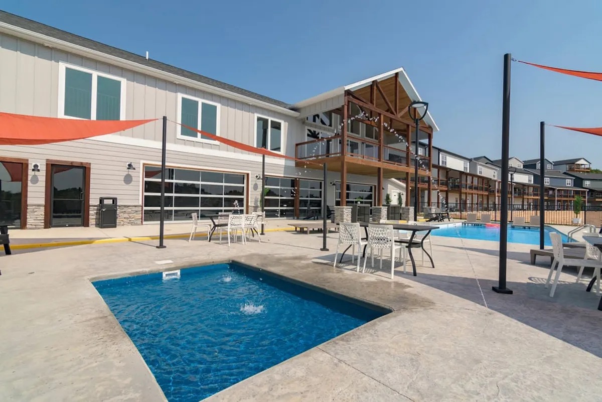 This exterior shot highlights the resort's vibrant outdoor pool area, with a sparkling swimming pool, jacuzzi, ample seating, and a view of the building’s facade. The scene is lively and social, ideal for families seeking relaxation and fun under the sun.