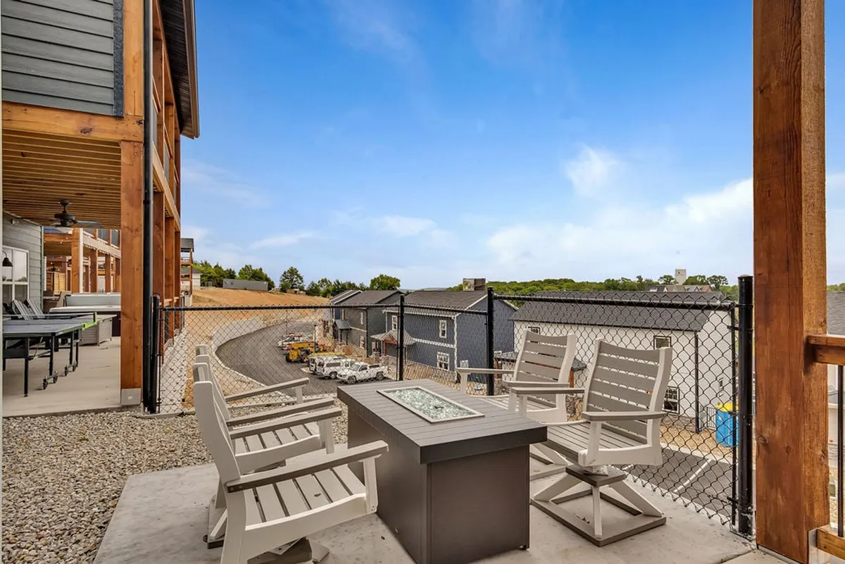 An inviting outdoor seating area arranged around a glowing gas fire pit, surrounded by scenic landscaping. Comfortable chairs are set up for group gatherings, with the backdrop of open sky and natural vistas hinting at both relaxation and lively conversation.