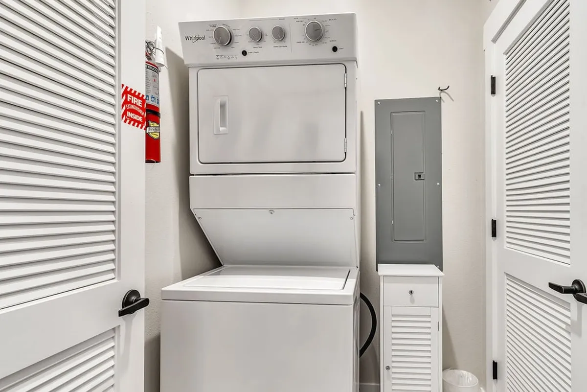 This interior shot displays a stacked washer and dryer in a clean, practical laundry space, equipped with necessary utility features. It highlights convenience and attention to cleanliness for guests.